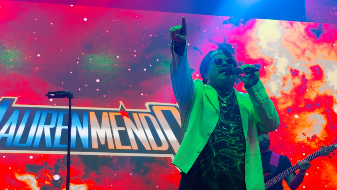 Performer sings into microphone on stage with colorful background